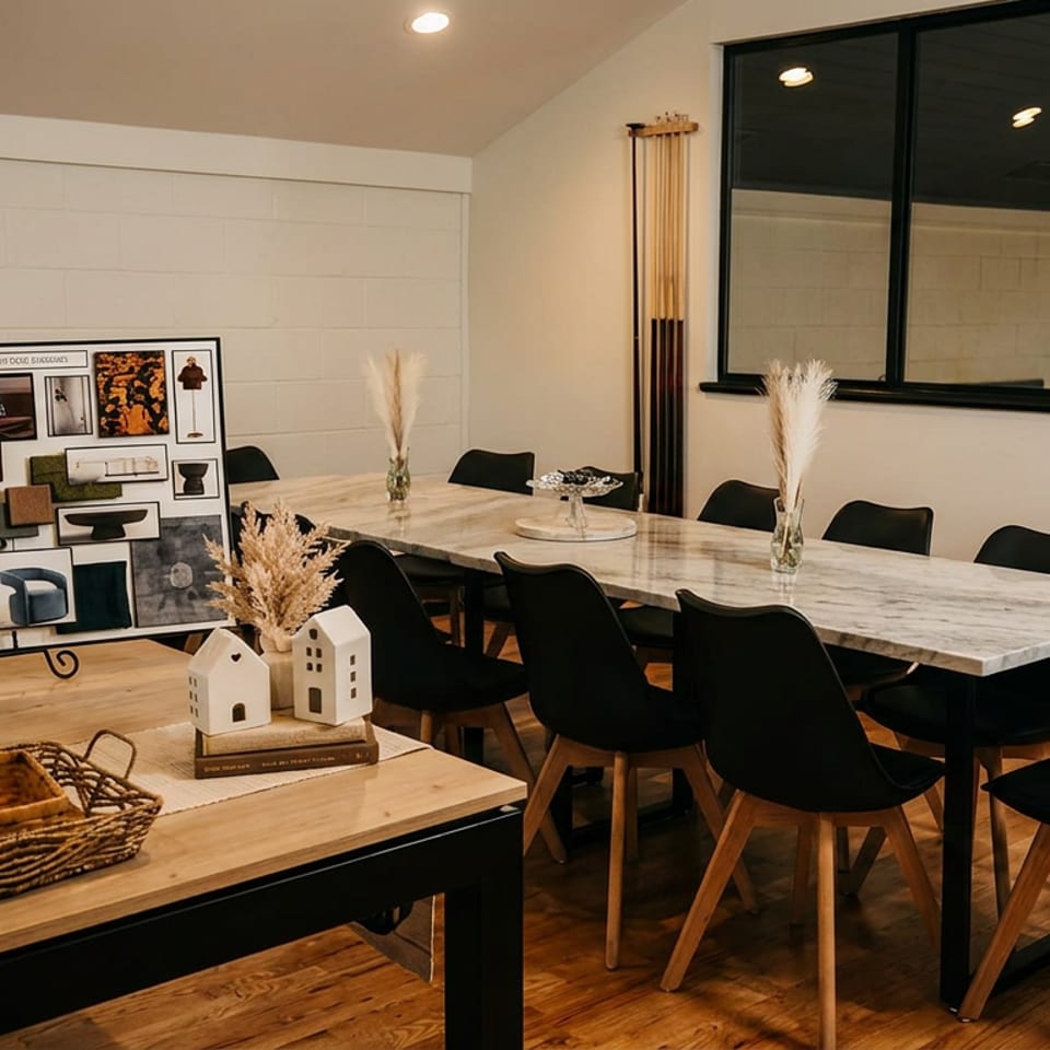 Warmly lit restaurant dining room with marble tables, black chairs, decorative vases, artwork, and pendant lights.