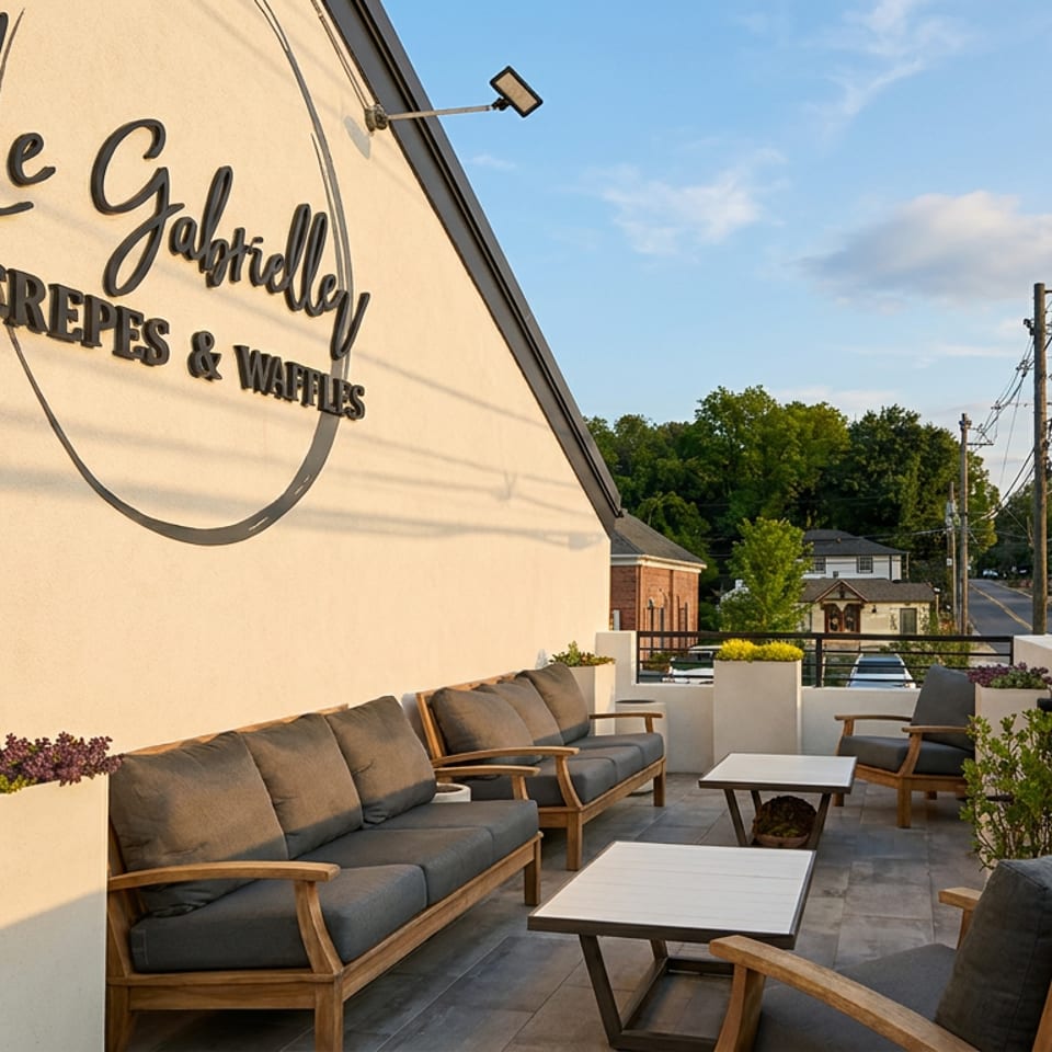 Outdoor terrace at Le Galette, a crepes and waffles restaurant, featuring cushioned seating, tables, planters, and a neighborhood view.